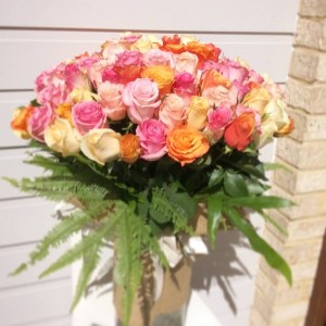 a large cylinder vase filled with 100 roses in pink and peach.