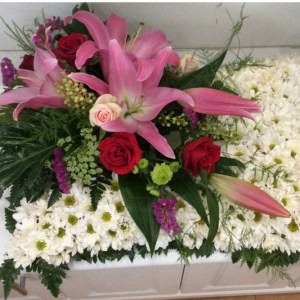 a sympathy pillow tribute of white dasies with a pink oriental lily and red rose feature on the left