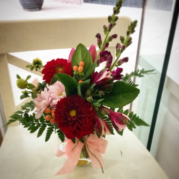 a jar filled with red and pink flowers.- A Touch of Class Florist