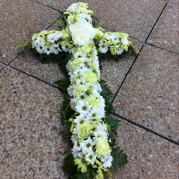 a white sympathy cross made using white and green seasonal flowers.