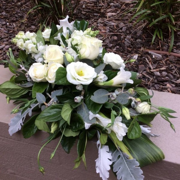 a full casket spray funeral tribute with white and green flowers