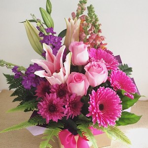 Hot Stuff Box Arrangement, in pink, purple and a touch of orange blooms.- A Touch of Class Florist