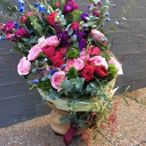 a large front facing hand tied bouquet in pink, purple and green.