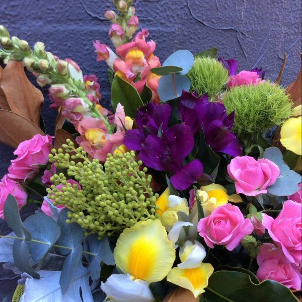 a bright bunch of seasonal flowers and foliage in pink, purple, yellow and green.