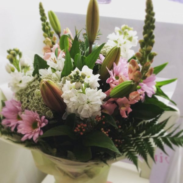 a pastel hand tied bouquet of seasonal flowers in pink, white and lilac.