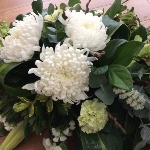 a full casket spray funeral tribute with white and green flowers