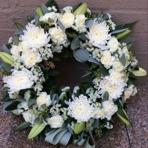 a large wreath made using white seasonal flowers with green foliage