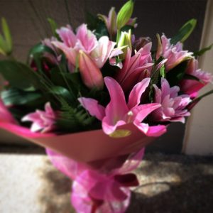 a large hand tied bouquet of pink oriental lilies wrapped in burgundy and pink