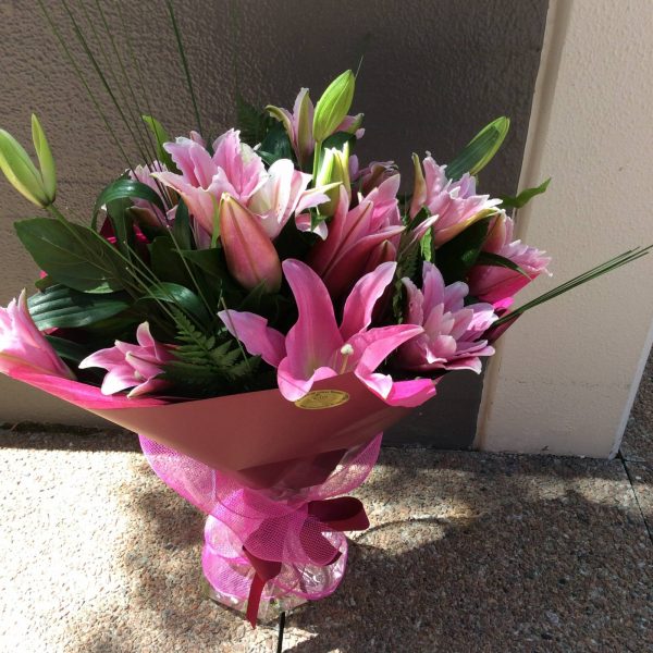 a large hand tied bouquet of pink oriental lilies wrapped in burgundy and pink