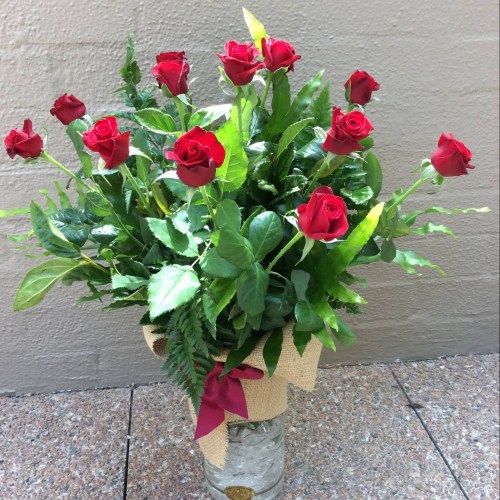 a glass vase filled with 12 long stem red roses.