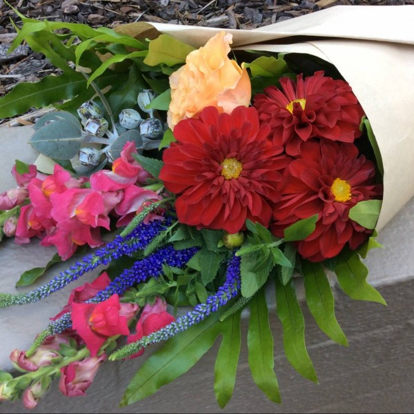 a seasonal wrap of bright flowers in red, pink and peach. wrapped in brown paper.