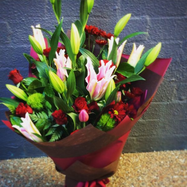a large bouquet of pink oriental lilies, red roses and other seasonal flowers- A Touch of Class Florist.