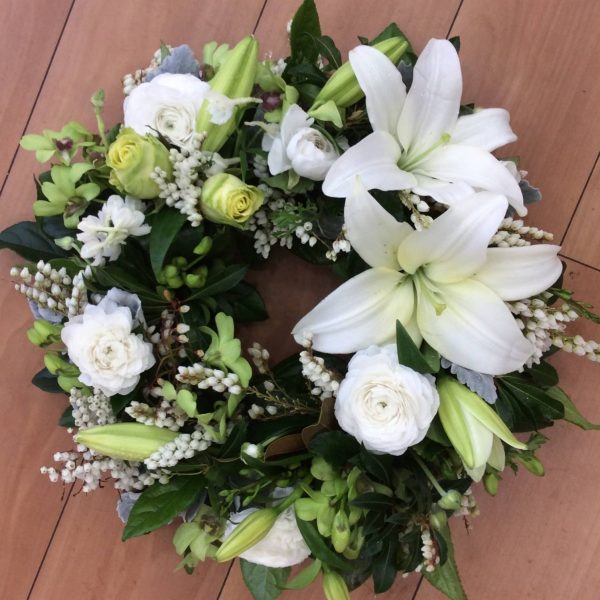 a wreath made using white flowers with open lilies as a feature.