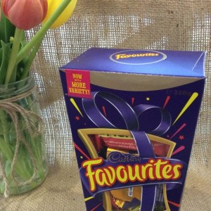 A box of Cadburys Favourites chocolates 320g with a jar of tulips in the background
