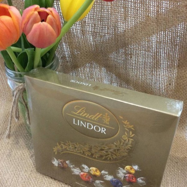 A 150g of Lindt chocolates on a hessian background with a jar of tulips shown behind.