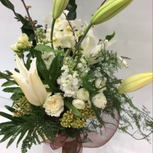 a sturctural vase arrangement of white seasonal flowers, sticks and loose floiages.