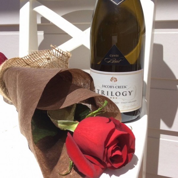 a single red rose wrapped in neutral paper and hessian with a bottle of sparkling wine- A Touch of Class Florist