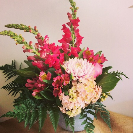 A seasonal posy style arrangement of the best blooms in pink displayed in a stylish ceramic vase.
