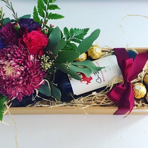 Just For You Gift Hamper includes a bottle of Red Wine, a cute desk sized flower arrangement in a ceramic jar and 6 ferrero Rocher chocolates gift wrapped in a bamboo box