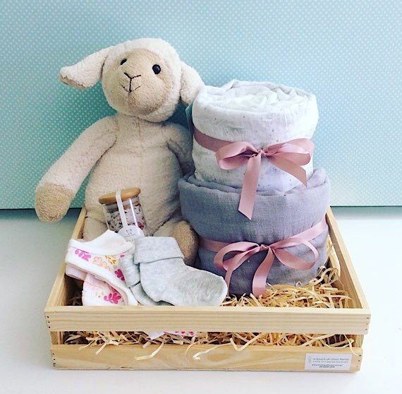 Little Lamb Baby Hamper in Pinks includes Sophie Sheep from Nana Huchy, 2 x baby wraps, newborn nappies, Sated Bliss Bath Salts, 2 items of baby clothing all wrapped up in a rustic wooden crate - A Touch of Class Florist