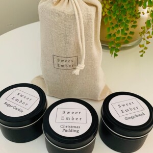 Sweet Ember Christmas Set contains three mini festive scented candles in black tins packaged in a natural calico bag.